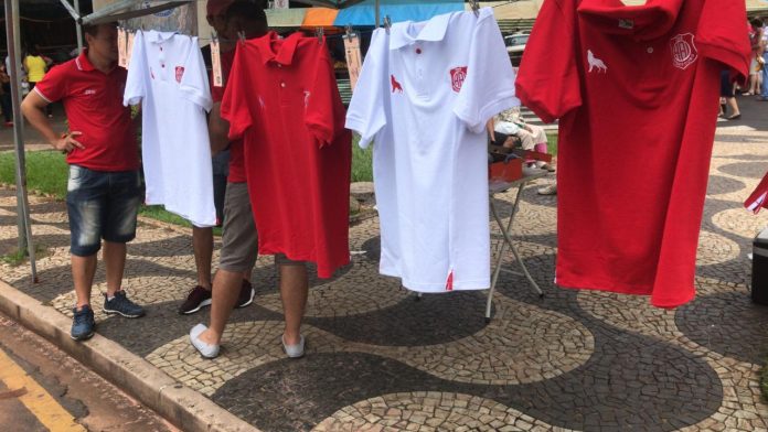 Amor a camisa – Passaportes e camisas da Inter são vendidos em quiosque na feira e na rua do comércio.
